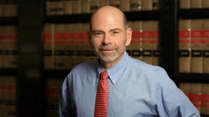 William J. Genego standing in front of legal books