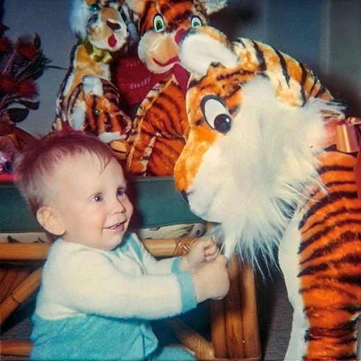 Me with a big stuffed tiger, surrounded by more tigers in the background - 1965.