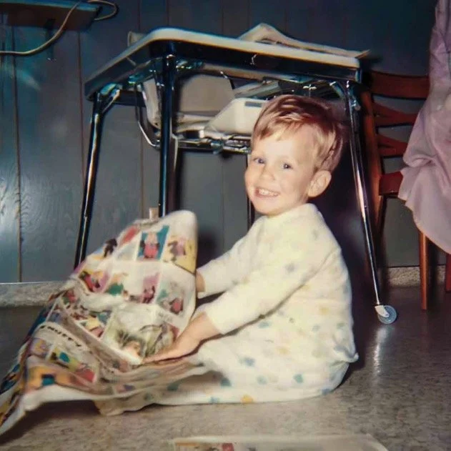 Happily reading the funny papers on the breakfast room floor - 1967.