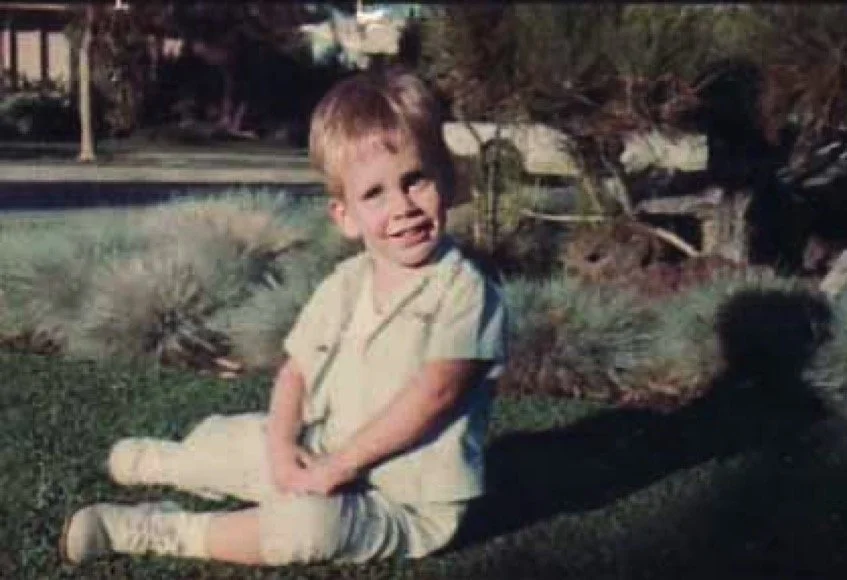Escaping the afternoon heat on the cool dichondra lawn of our Huston Street yard, with a Japanese White Pine and Blue Fescue ground cover behind me - 1967.