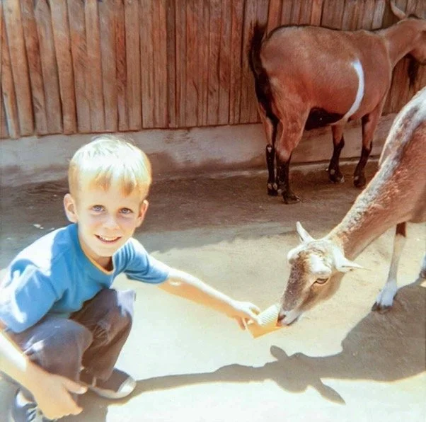 At the petting section of the Los Angeles Zoo. I still recall the smell of the dust, and the handfuls of animal feed pellets we could buy, and the feel of the animals' hot breath and snouts tickling my palm as I fed them - 1969